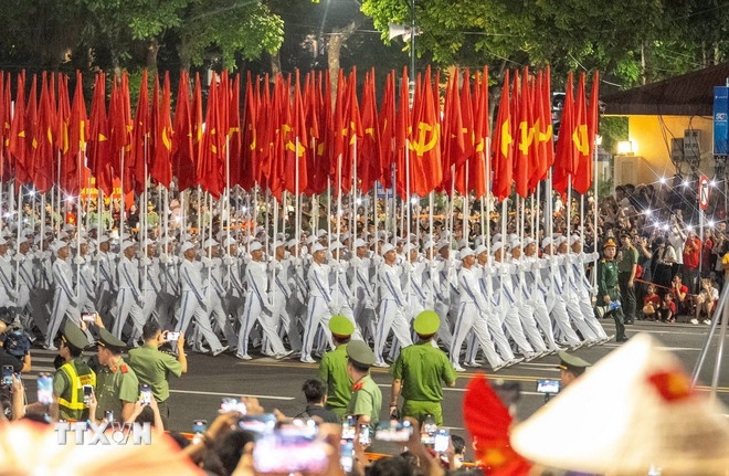   Khối hồng kỳ di chuyển trên đường phố Hà Nội. (Ảnh: TTXVN)
